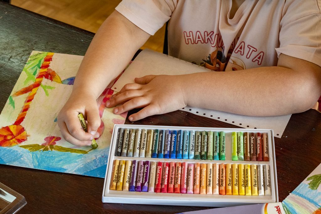A child drawing vibrant artwork using oil pastels on paper, focusing on creativity and art.