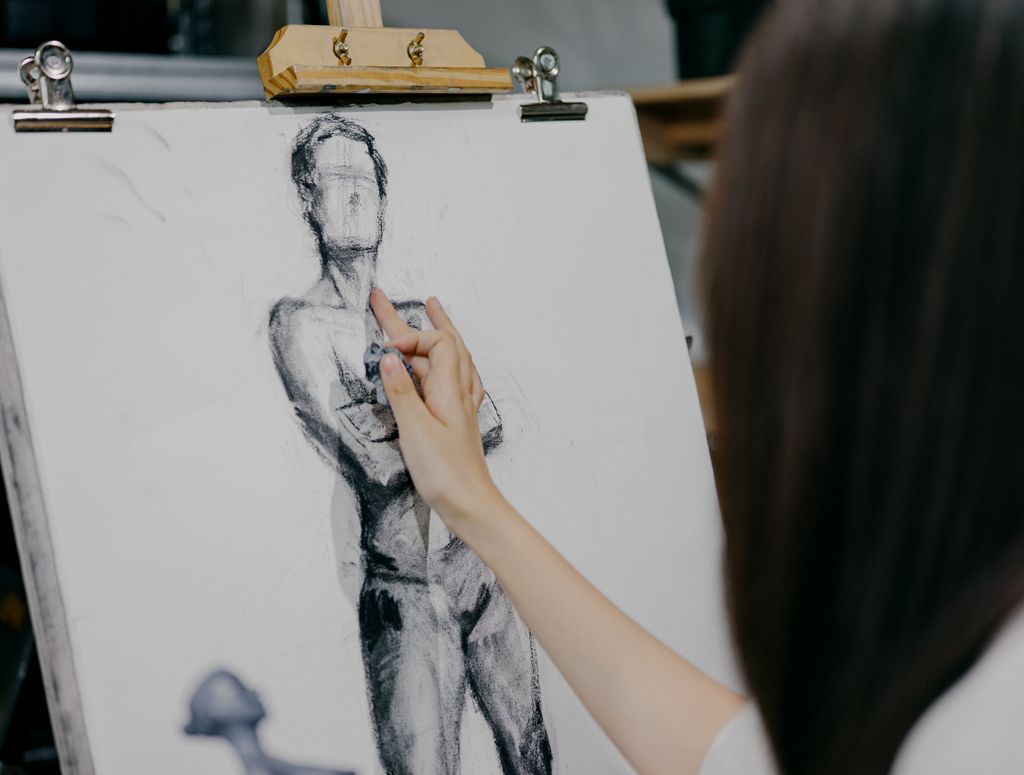 A focused artist sketching a human figure on canvas in a Shinjuku art studio in Tokyo, Japan.