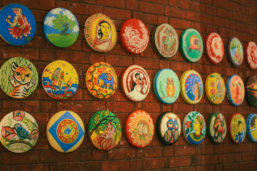 Vibrant traditional paintings on a brick wall in Dhaka, Bangladesh showcasing cultural heritage through diverse artwork.